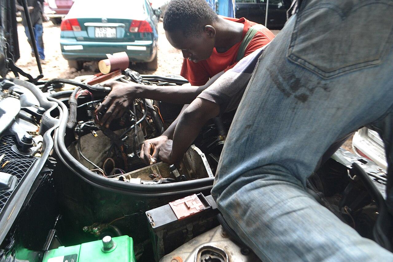 Two mechanics working on a car engine