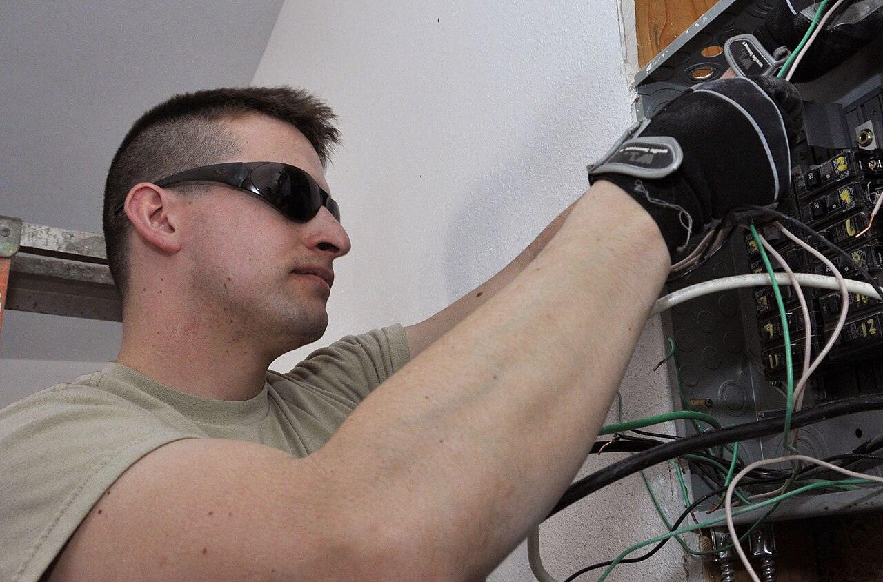 An electrician working on wiring in an open electrical box