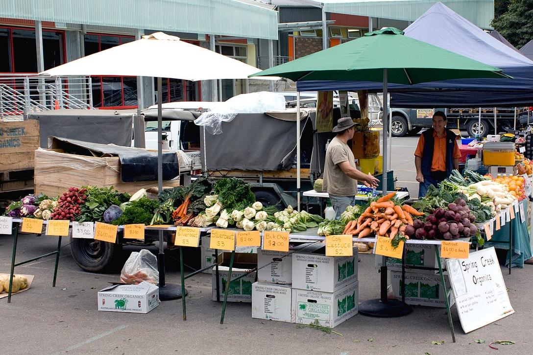 Vegetable stalls under canopies at a farmers market