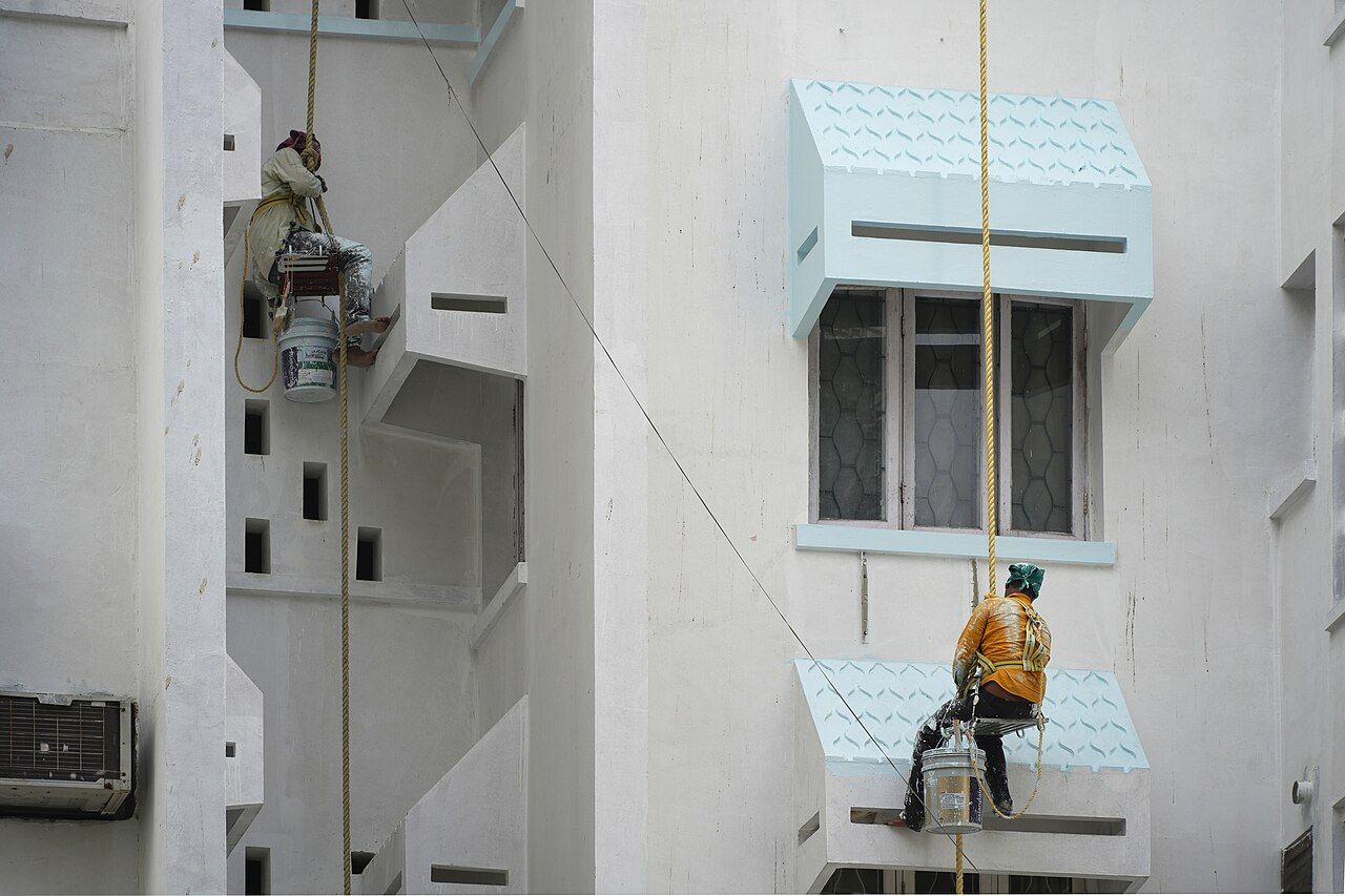 Painters on ropes painting the side of a building