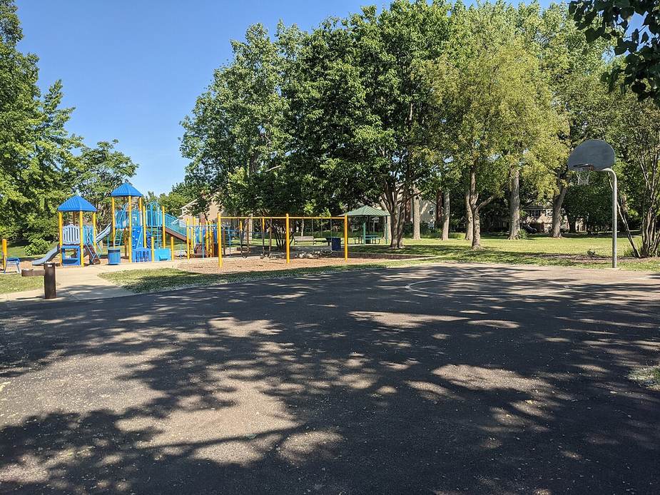 A playground and shade trees in a town park