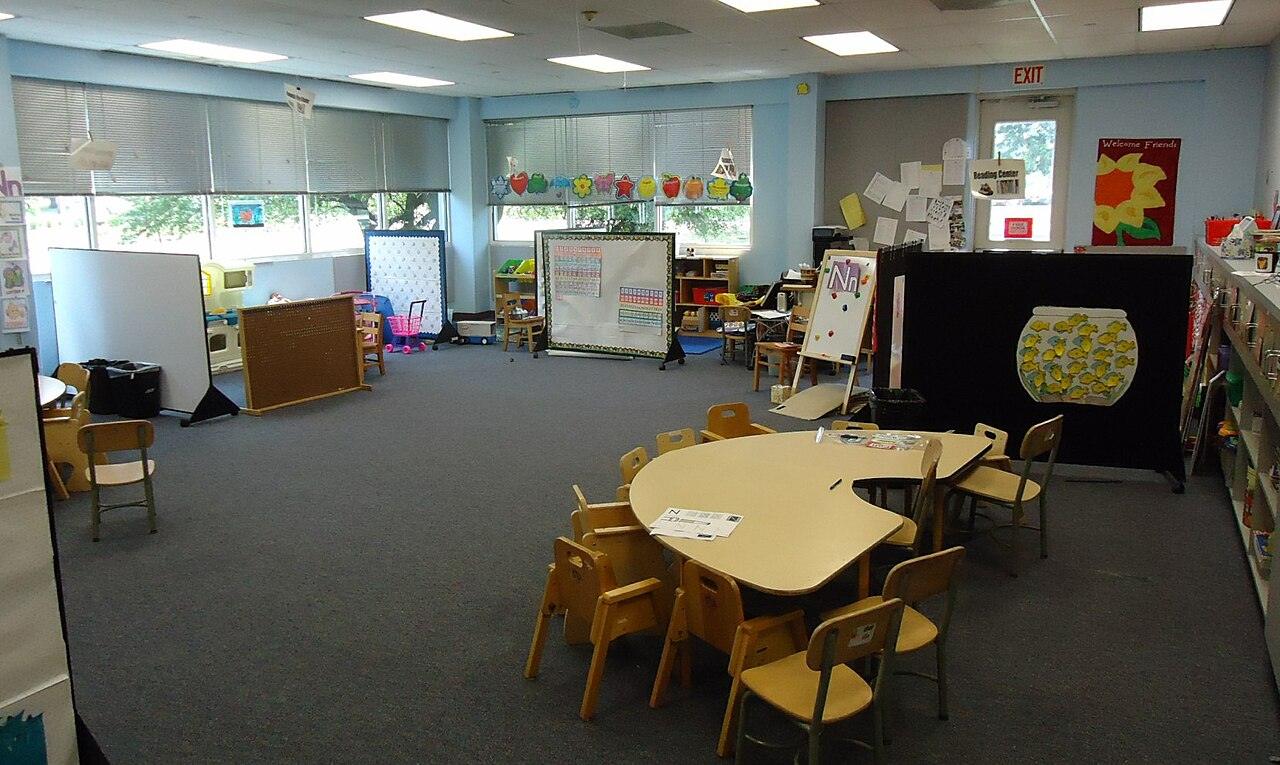 An empty preschool classroom with small tables and chairs