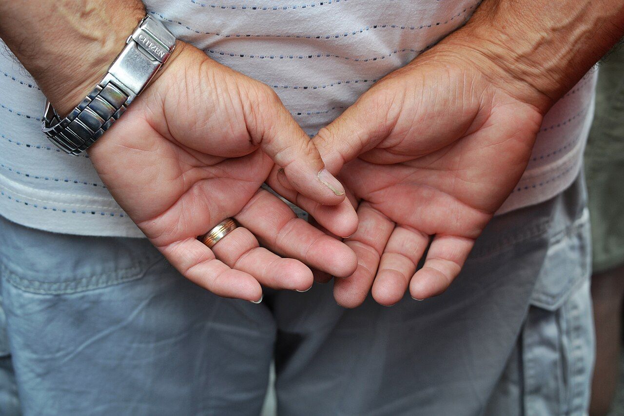 The folded hands of an older man