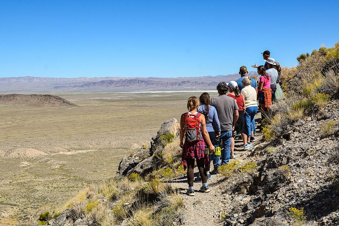 A tour group walking a trail on a desert hillside