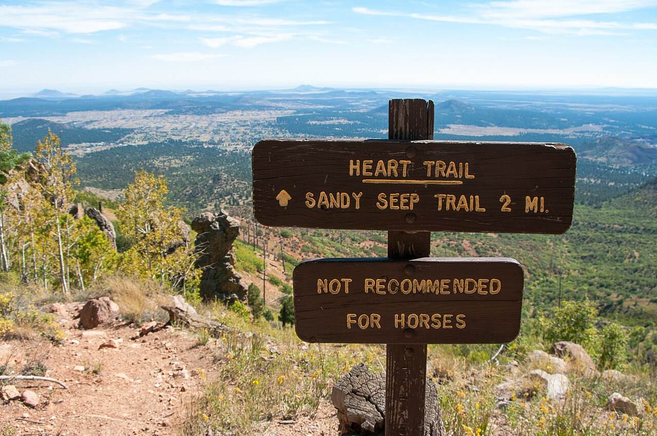 A wooden trail sign above a wide Arizona valley