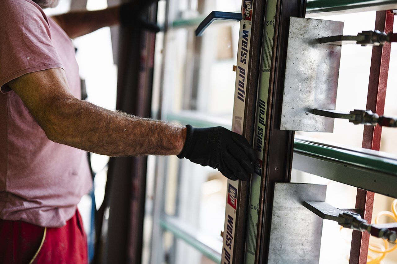 A worker fitting a window frame into a wall
